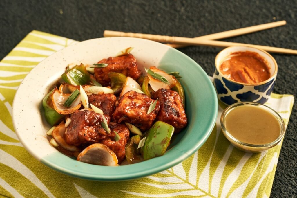 A vibrant bowl of stir-fried tofu with vegetables, garnished with green onions. Perfect for an appetizing meal.