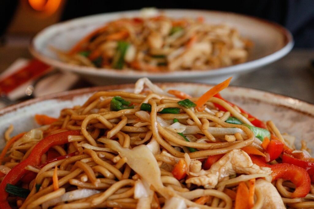 Close-up of flavorful stir-fried noodles with fresh vegetables and chicken.