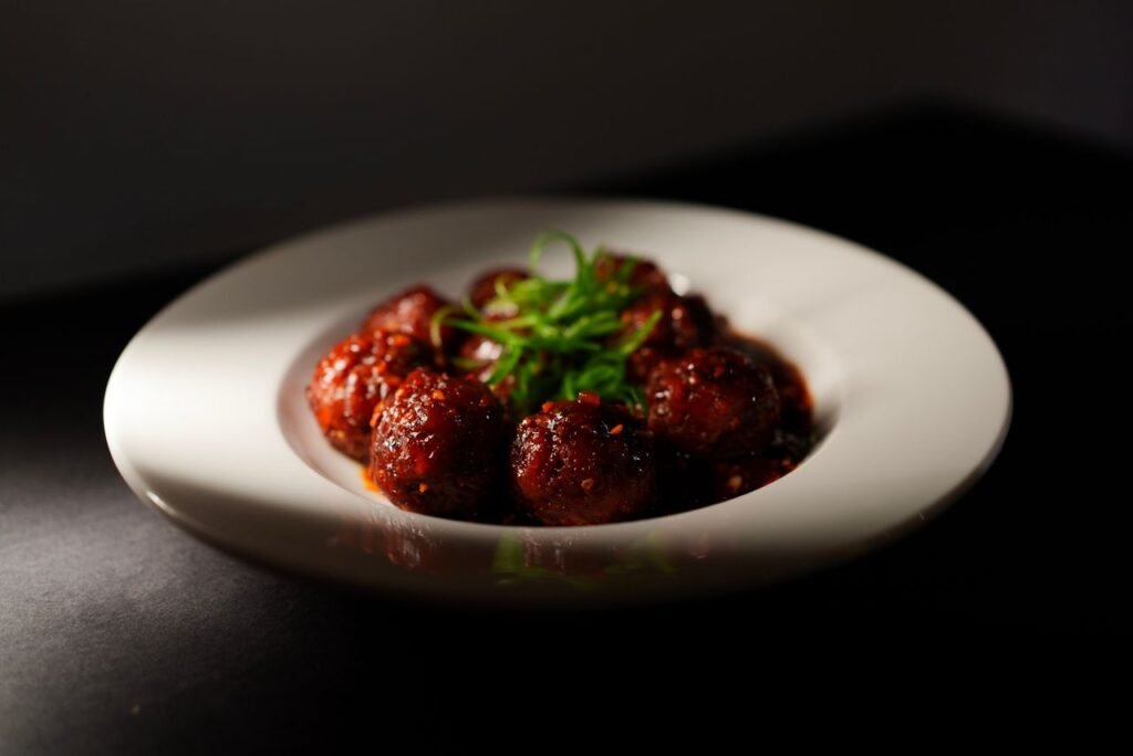 Close-up of flavorful Indo-Chinese vegetarian Manchurian served on a white plate, garnished with fresh herbs.