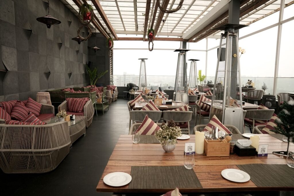 Stylish rooftop restaurant featuring modern decor, cozy seating, and a stunning city view. Perfect for dining.