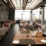 Stylish rooftop restaurant featuring modern decor, cozy seating, and a stunning city view. Perfect for dining.