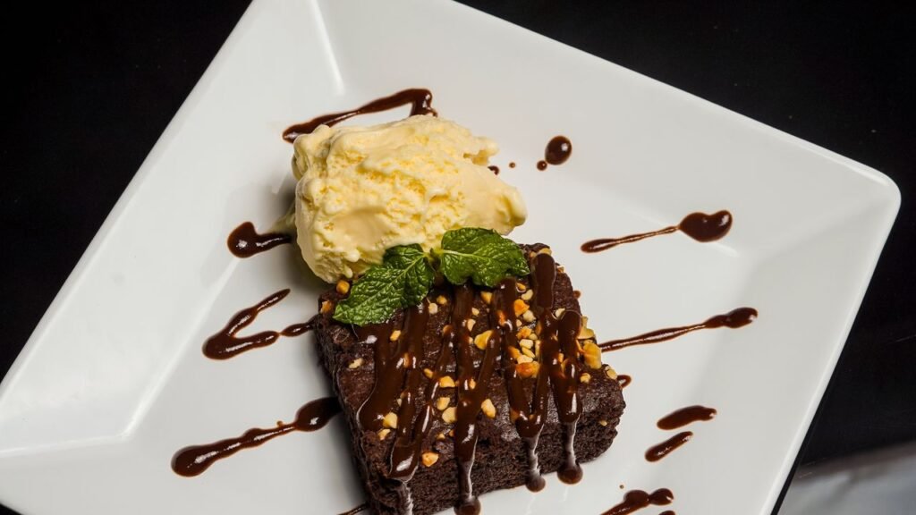 Top-down view of a chocolate brownie with vanilla ice cream and mint garnish.