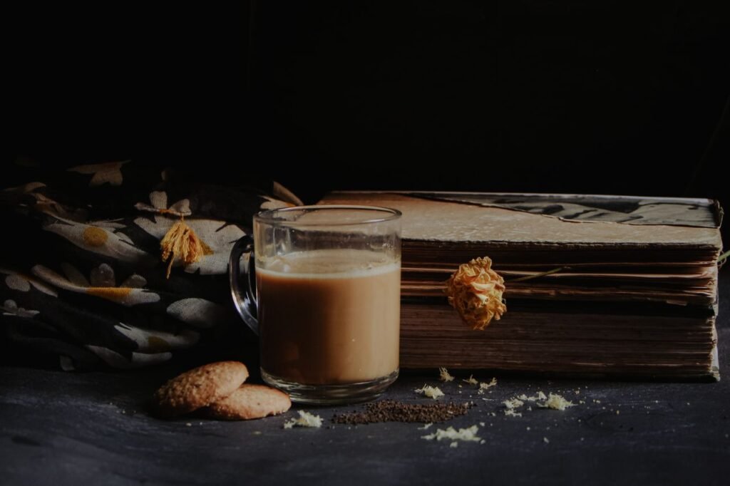 Dark atmospheric still life of a cozy tea setup with cookies and vintage books.