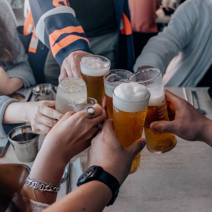 Close-up of friends toasting with assorted drinks at a gathering, capturing a moment of celebration and camaraderie.
